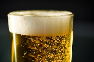 Пузырьки в стакане светлого пива с пеной, крупный план 