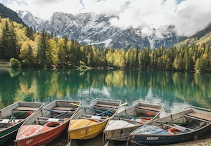 горное озеро, окруженное лесом и разноцветные лодки 