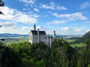 Впечатляющий снимок исторического замка Нойшванштайн, расположенного у подножия прекрасных Баварских Альп в Германии, лес, горы, облака, горный пейзаж днем 