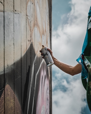 Художник распыляет краску из баллончика на настенную роспись 