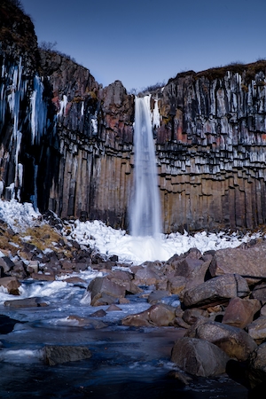 Один из многочисленных водопадов Исландии, Свартифосс, отвесный водопад посреди высоких отвесных скал, бассейн 