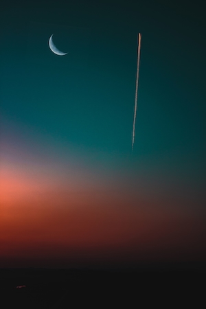 полумесяц, луна на небе во время заката в окружении облаков, след от самолета 