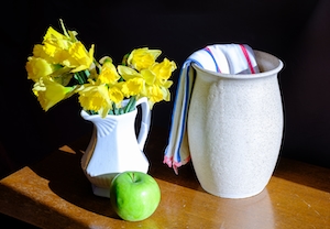 яркие цветы в белой вазе, зеленое яблоко и полотенце в кувшине 