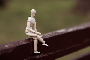 деревянная игрушечная модель, сидящая на скамейке