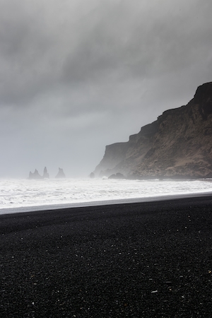 морской пейзаж, песчаный пляж с черным песком в пасмурную погоду 