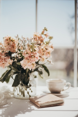 цветы в стеклянной вазе, блокнот и чашка кофе 