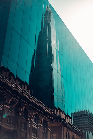 отражение небоскреба в стеклянном фасаде здания 
