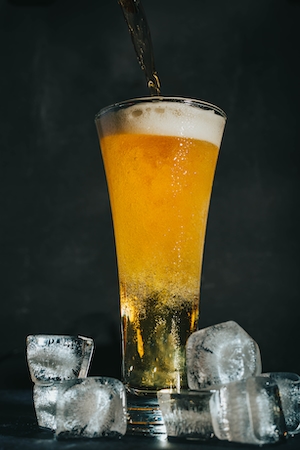 Пиво наливается в бокал с кубиками льда