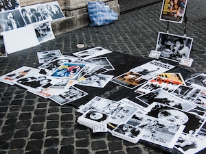 Рим, Италия: уличный продавец продает старые фотографии кинозвезд, рок-звезд и других личностей, разложенные на булыжниках 