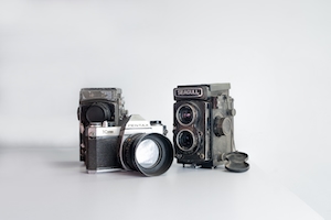 фотография черных старых фотоаппаратов на белом фоне 