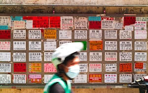 Стена объявлений о работе, доступных в Шэньчжэне, Китай, человек идет мимо постеров, плакатов на стене 