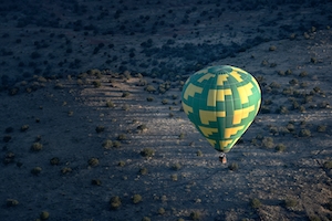 Воздушный шар, взлетающий над пустыней ранним утром