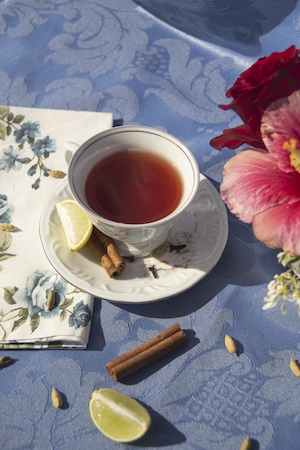 Чашка чая с корицей и лимоном на столе с голубой скатертью