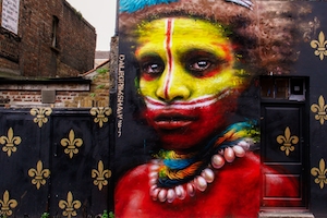 Уличный арт с изображением лица аборигена, нарисованного на стене дома.