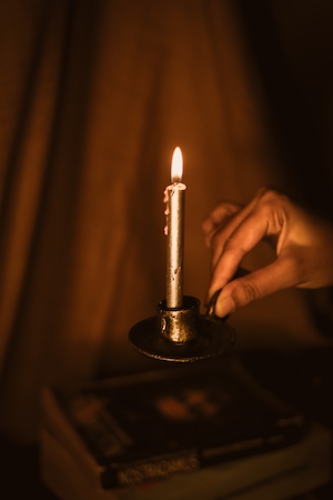 Атрибутика Гарри Поттера, вещи в стиле Гарри Поттера, горящая свеча и рука человека 