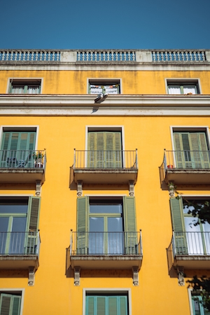 Желтое здание с зелеными ставнями на окнах 