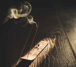 Индийская масала, горящая ароматическая палочка с белым дымом на деревянной темной поверхности