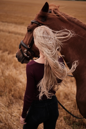Лошадь и женщина, стоящие на стерневом поле 