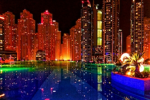 Офисы и отели освещены и отражаются в бассейне в Дубай Марина.