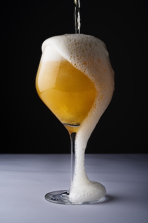 Пиво переливается через край из стакана