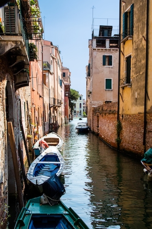 Узкий канал в венеции днем, здания на воде, гондола 