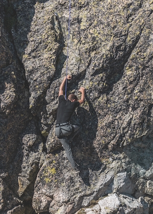 Молодой спортсмен-любитель, занимающийся скалолазанием, парень на скале 
