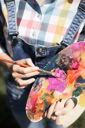 художник набирает цвет на кисть с палитры 