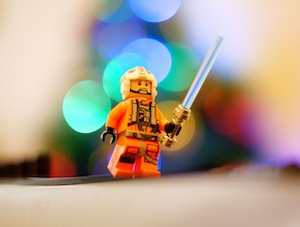 Конструктор Lego Люк Скайуокер держит свой световой меч перед рождественской елкой.