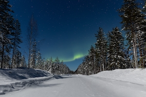 Красивое северное сияние, известное как северное сияние и залитый лунным светом зимний пейзаж в Финляндии