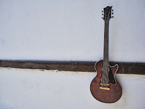 старая гитара, висящая на белой стене