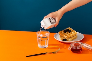 рука человека наливает воду из белой коробки, предметная съемка завтрака 